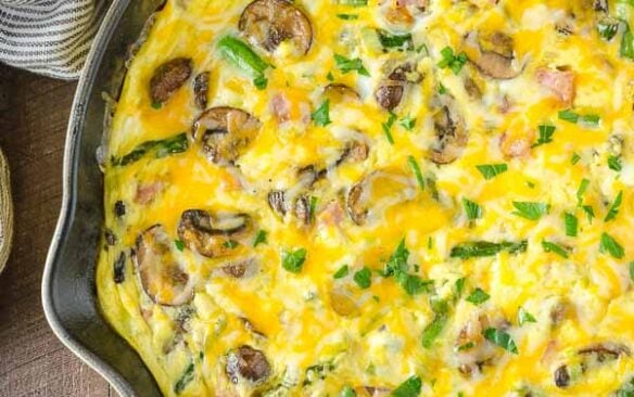 A ham, asparagus and mushroom frittata in a skillet.