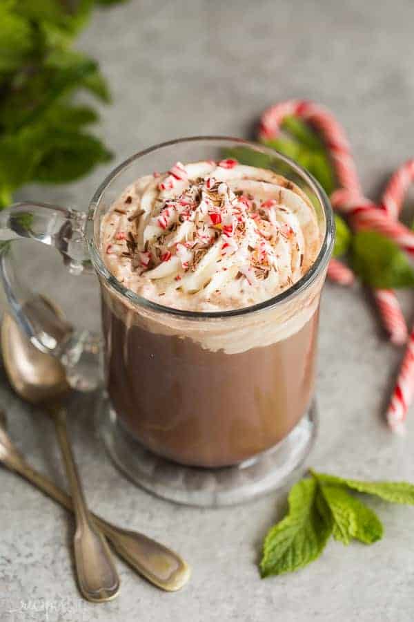 peppermint mocha with whipped cream and crushed candy canes on top and two spoons on the side