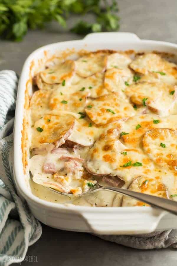 cheesy scalloped potatoes and ham recipe close up from the side with metal spoon stuck in potatoes