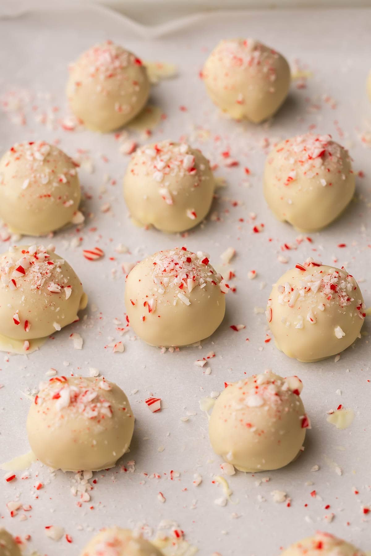 white chocolate oreo truffles with crushed candy canes on a baking sheet.