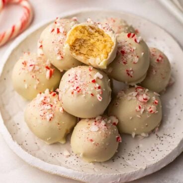 square image of a stack of white chocolate oreo truffles with a bite taken out of one.