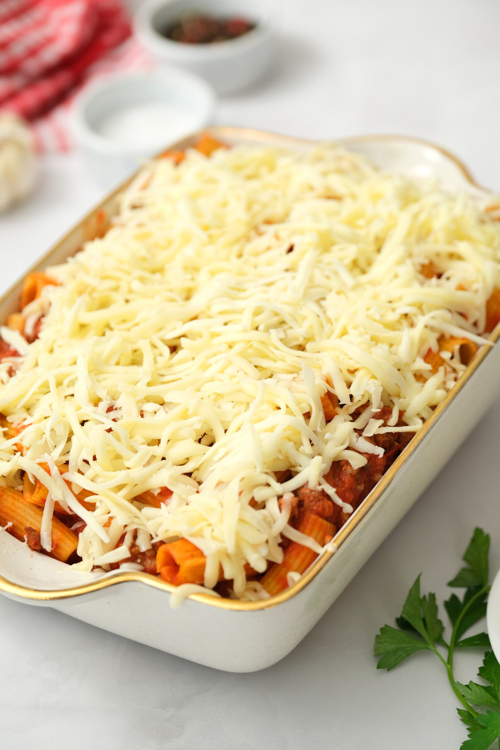 shredded cheese on top of rigatoni in pan.