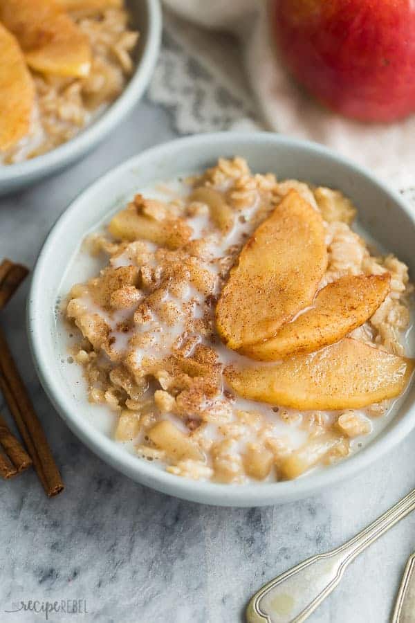 apple cinnamon oatmeal with milk and sauteed apples on top and apples in the background