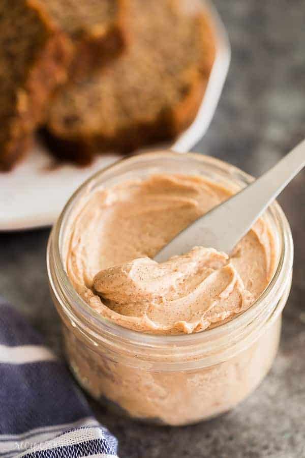 cinnamon butter in jar with knife scooping some butter and banana bread in the background