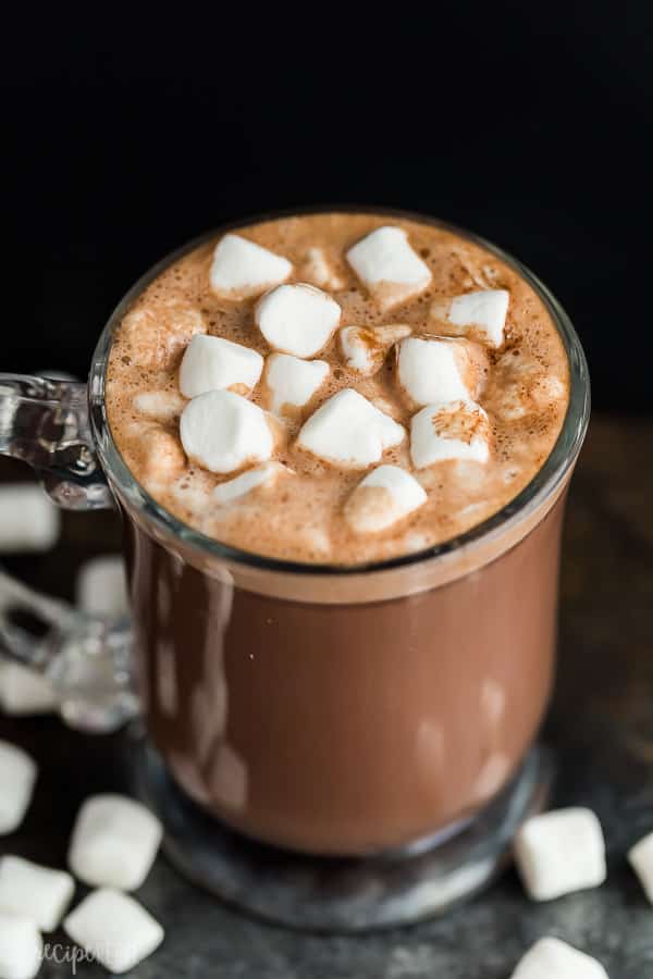 crockpot hot chocolate in glass mug with mini marshmallows on top on black background
