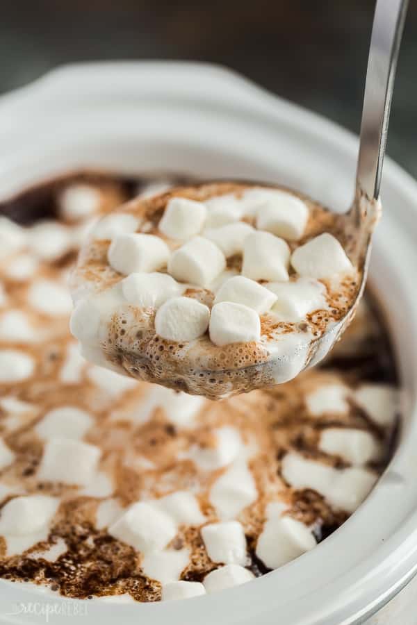 crockpot hot chocolate in ladle coming out of slow cooker with mini marshmallows on top