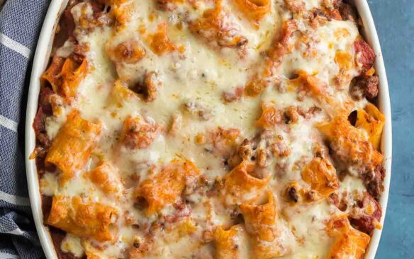 rigatoni pasta bake in white baking dish with blue towel on the side.