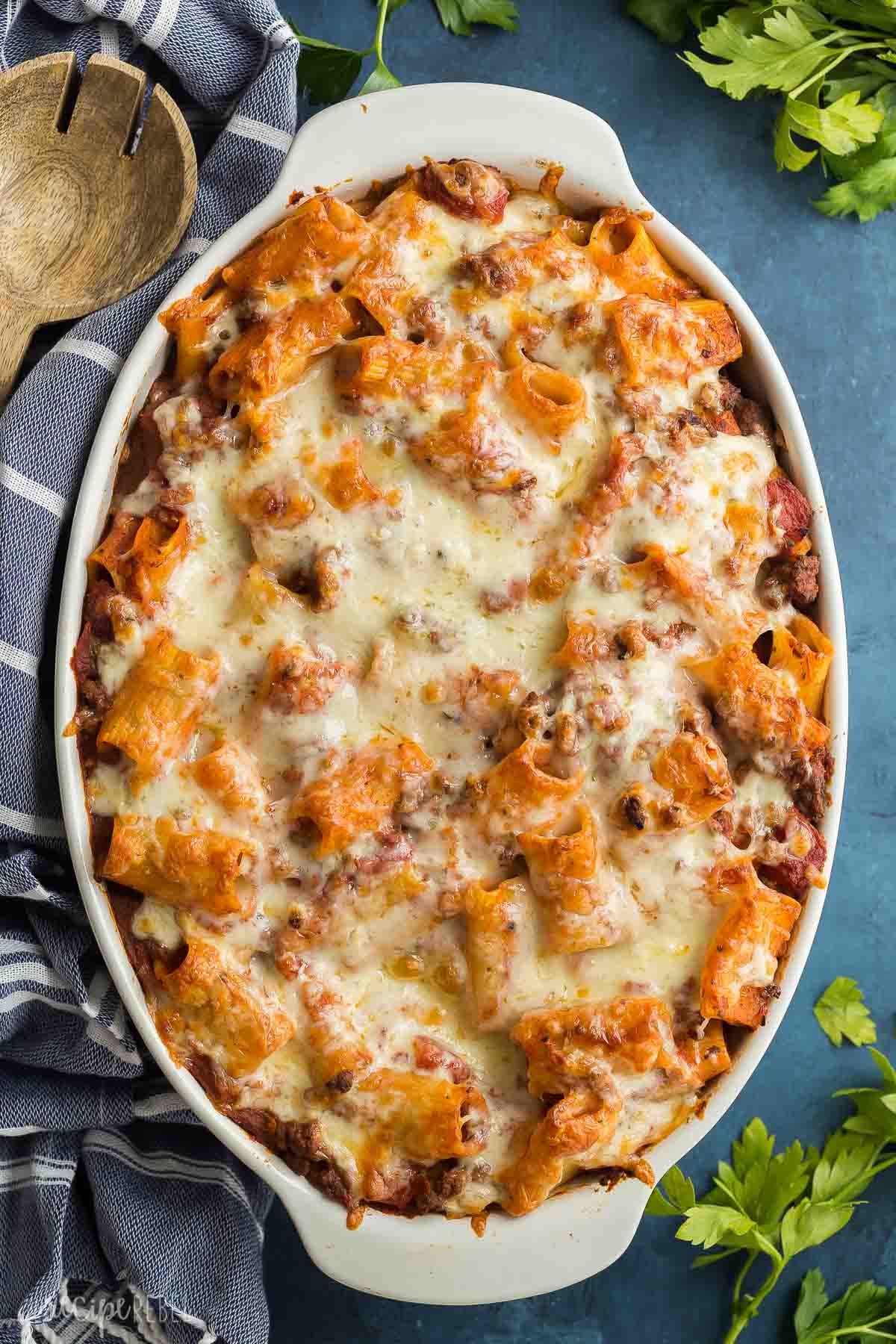 rigatoni pasta bake in white baking dish with blue towel on the side.