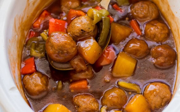 ladle scooping sweet and sour meatballs out of crockpot