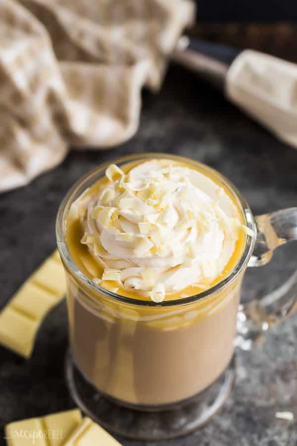 white chocolate mocha in glass mug with whipped cream and chocolate shavings close up on dark grey background