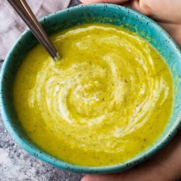 close up image of broccoli ginger soup in blue bowl