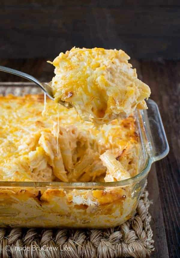 buffalo chicken pasta bake in clear glass baking dish with metal spoon pulling up a scoop