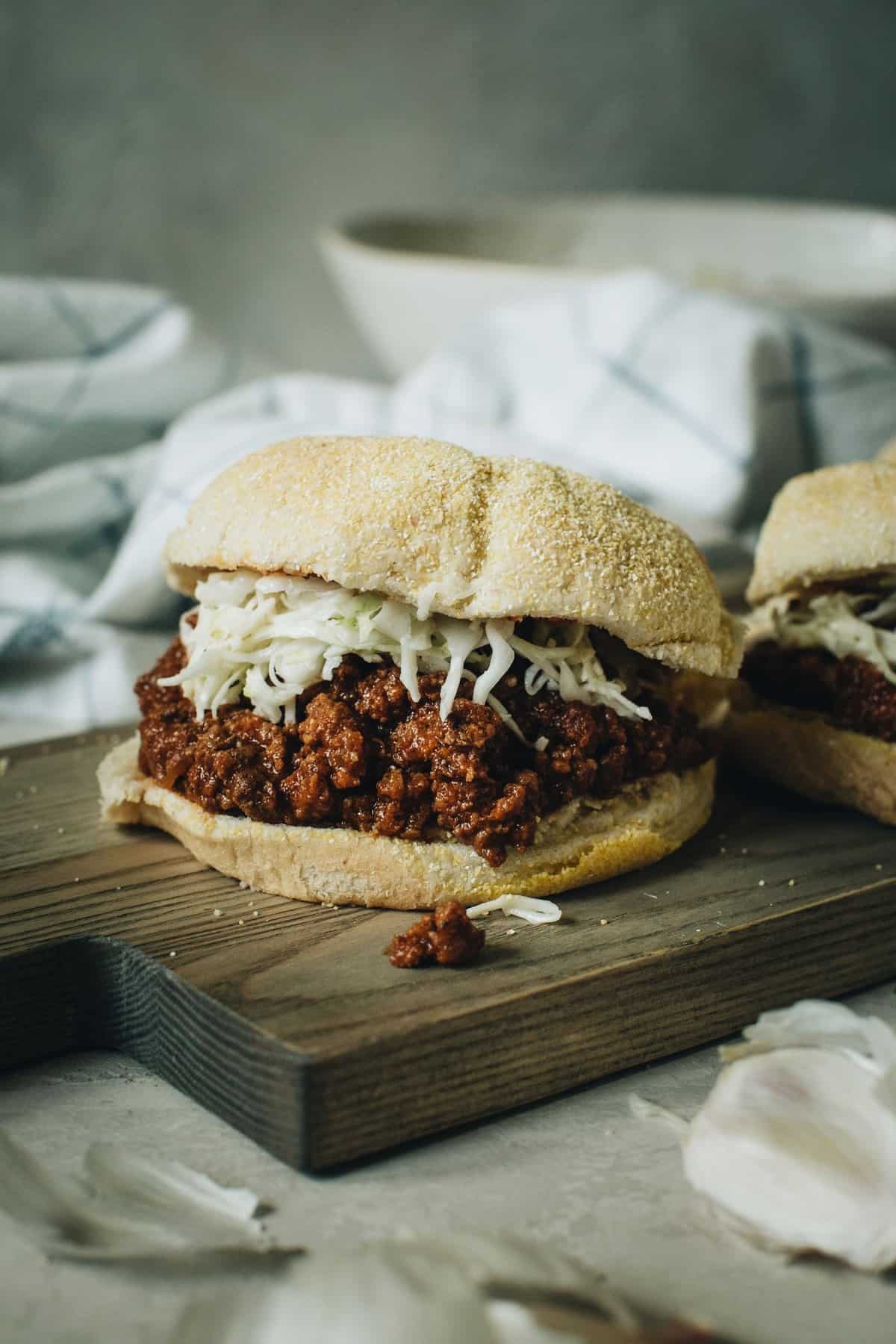 sloppy joes with white shredded cheese on white bun with white towel in the background