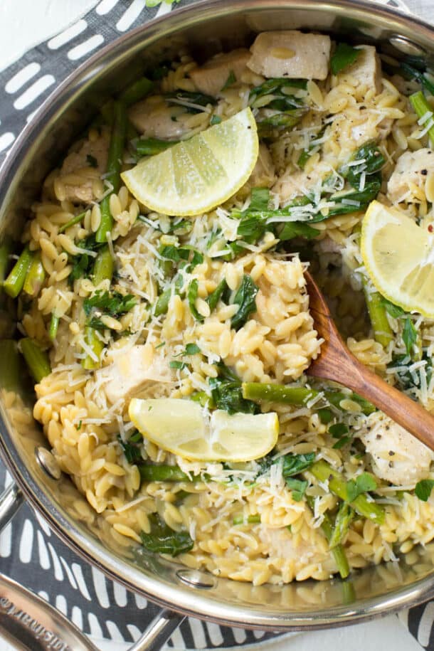  one pot lemon chicken orzo overhead with wooden spoon in pan and lemon slices