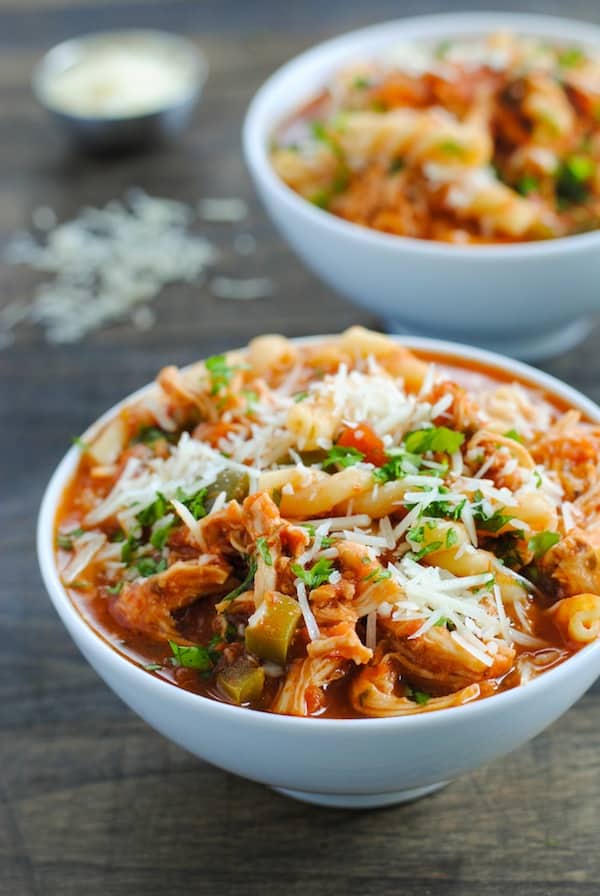 chicken parmesan crockpot soup in white bowl close up on wood background with shredded Parmesan cheese