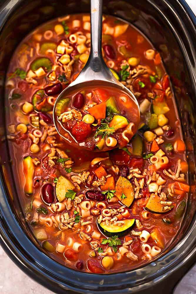 pasta e fagioli crockpot soup in black crockpot with a metal scoop in the soup