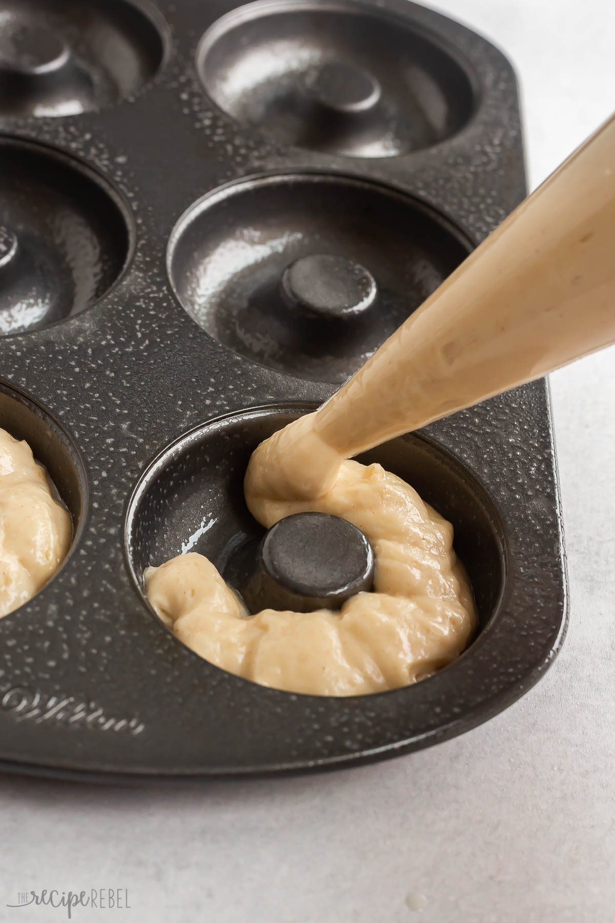 donut batter being piped into donut pan.