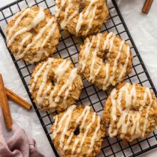 six apple crisp donuts on black cooling rack with glaze.