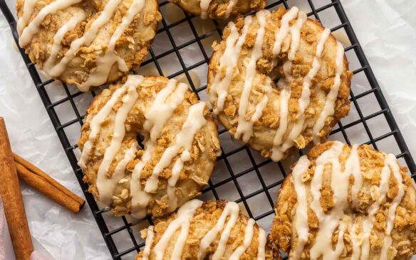 six apple crisp donuts on black cooling rack with glaze.