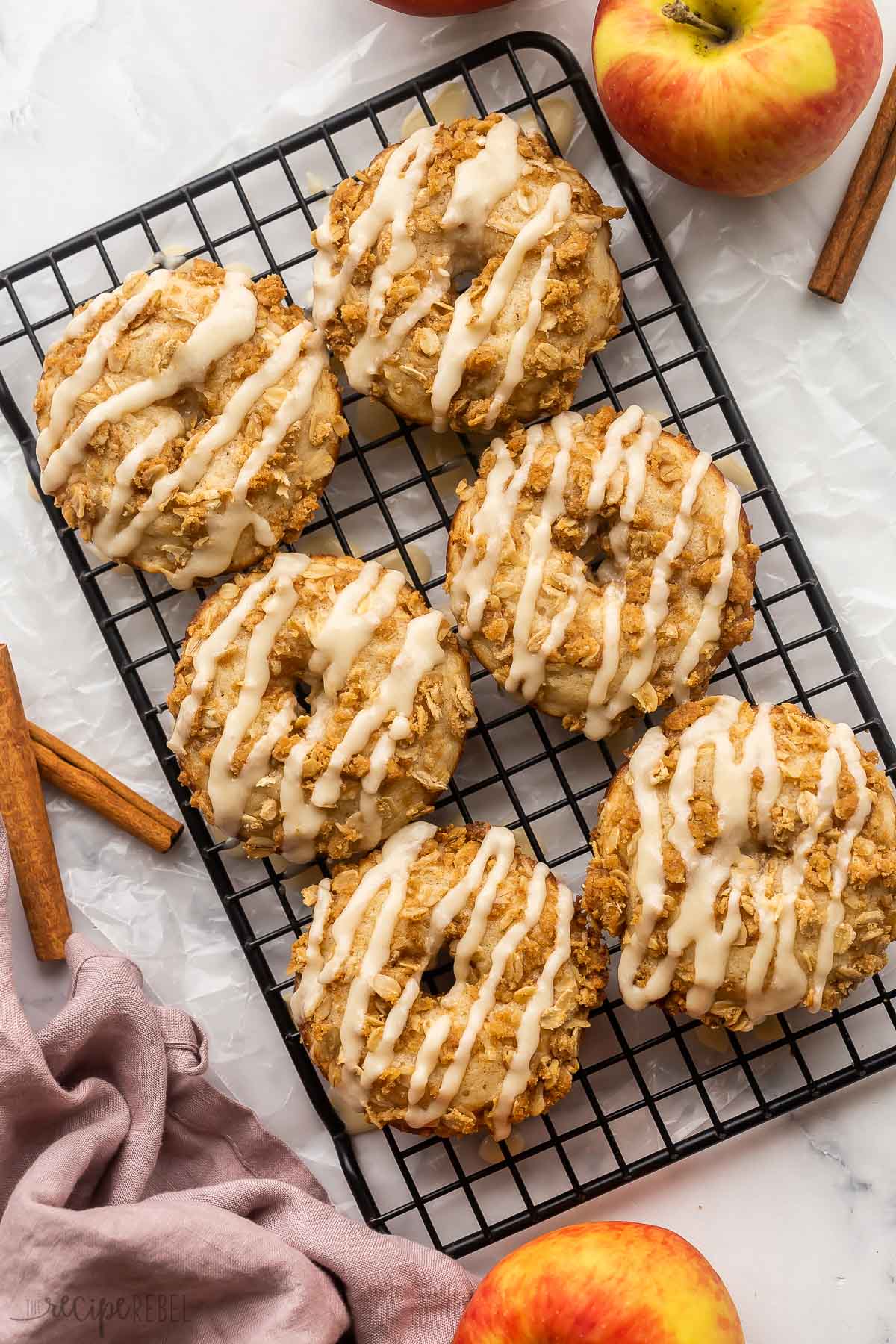 six apple crisp donuts on black cooling rack with glaze.