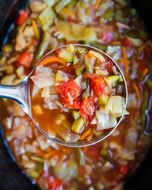 slow cooker cabbage soup close up of a metal scoop over top of a slow cooker