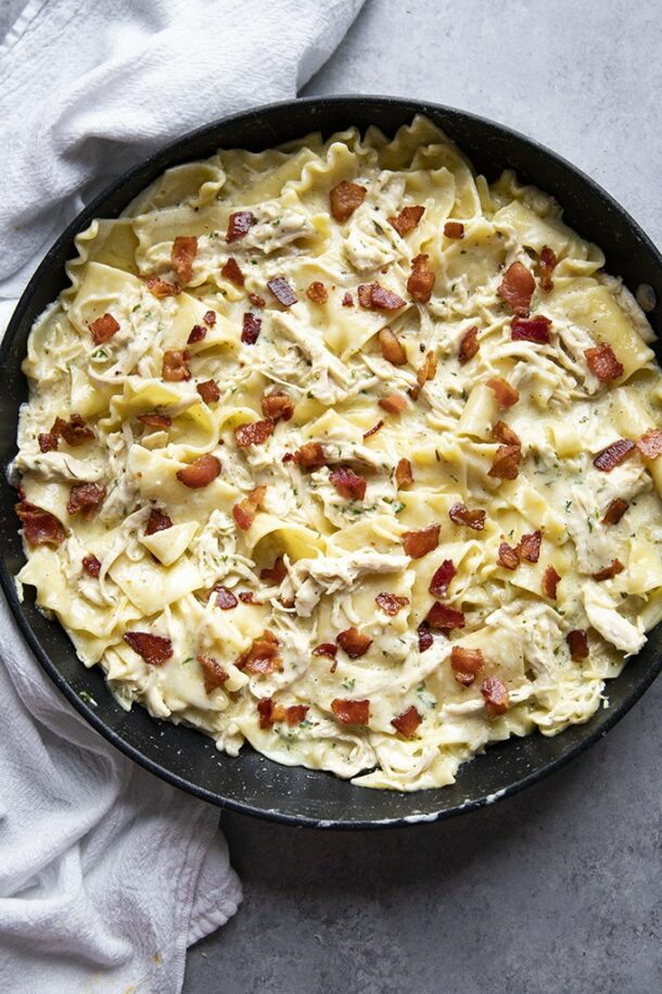 one pan chicken lasagna overhead in black pan with crispy bacon on top