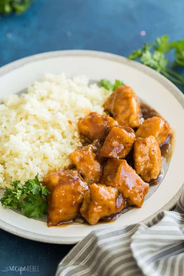 crockpot orange chicken with rice close up on grey plate on blue background