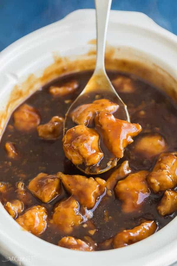 crockpot orange chicken in slow cooker with metal scoop scooping some out