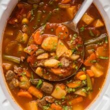 overhead image of beef vegetable soup in crockpot with metal ladle