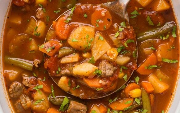 overhead image of beef vegetable soup in crockpot with metal ladle