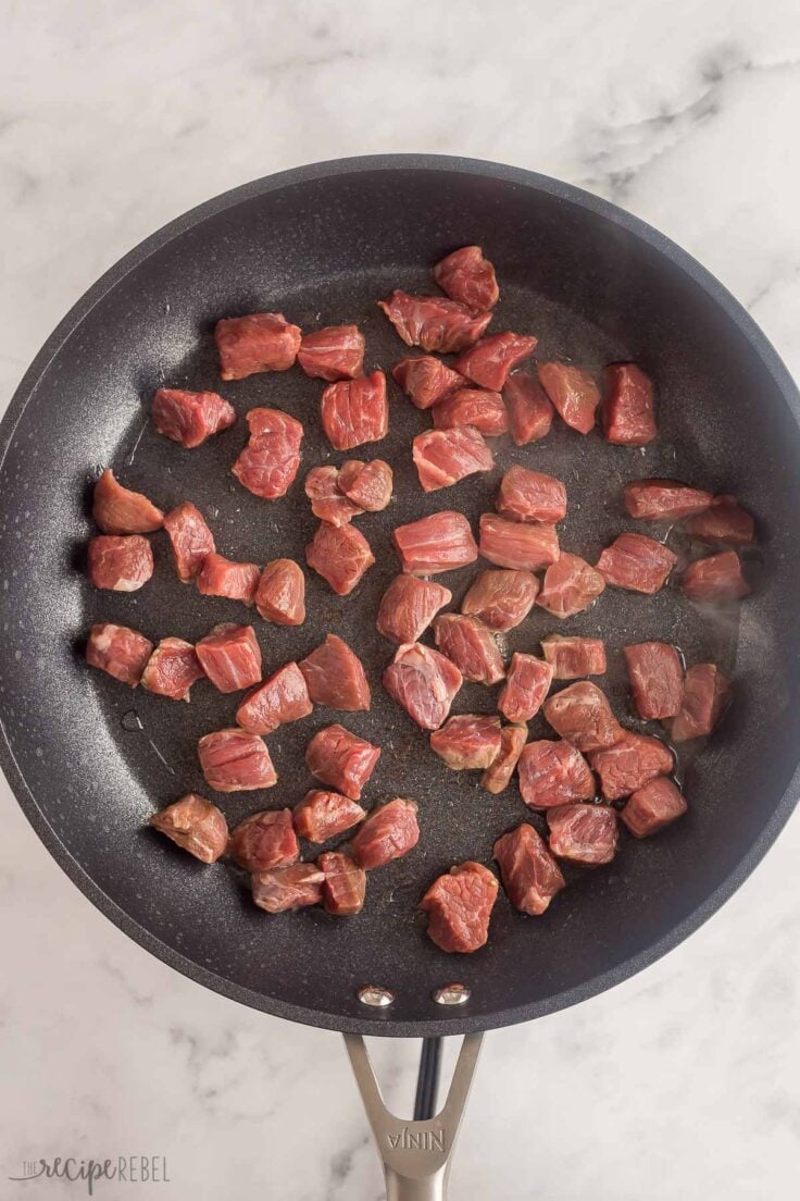 uncooked beef cubes in black skillet ready to cook