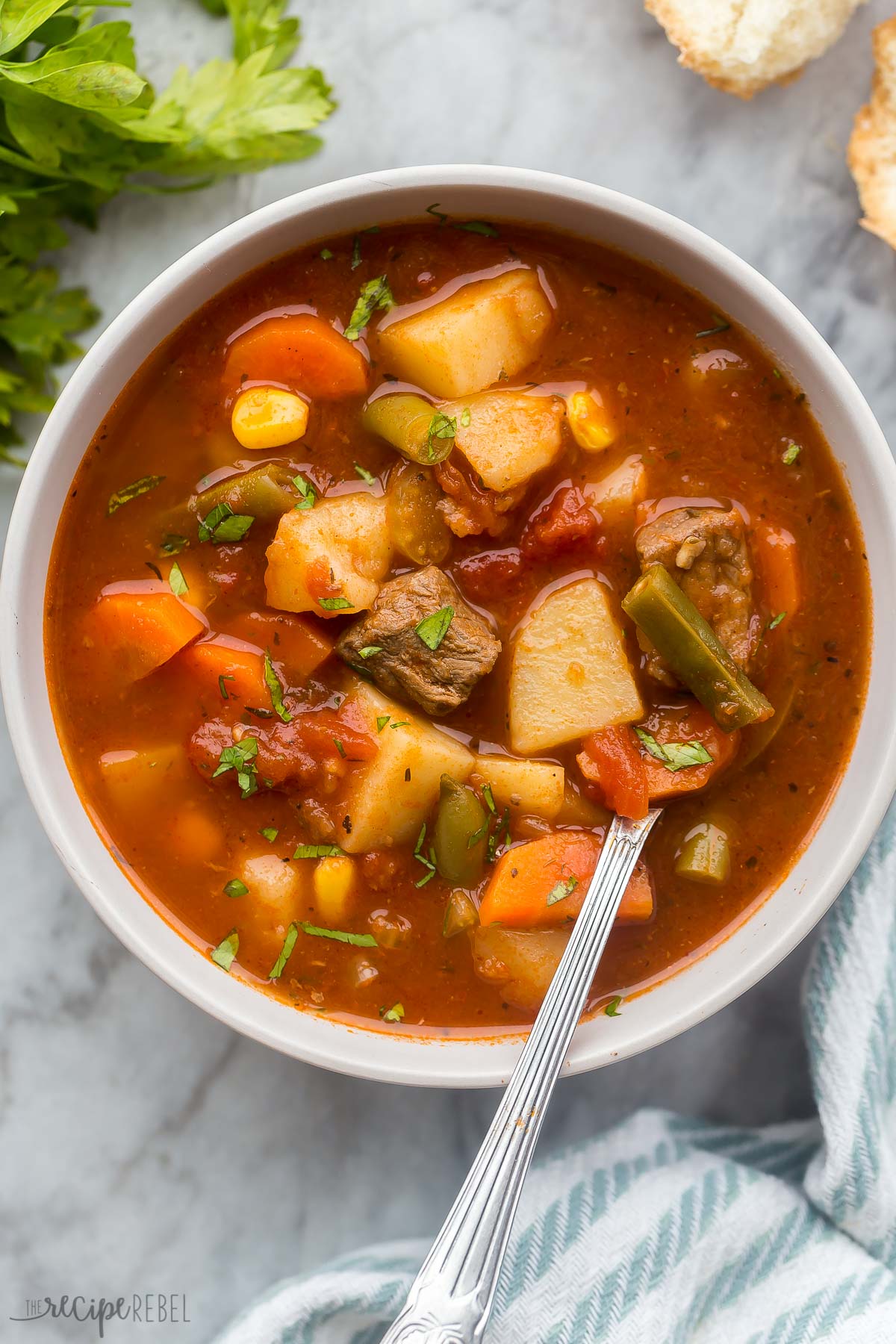 overhead image of crockpot vegetable beef soup in bowl with spoon