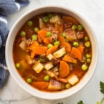 square image of hamburger soup in bowl with blue towel on the side