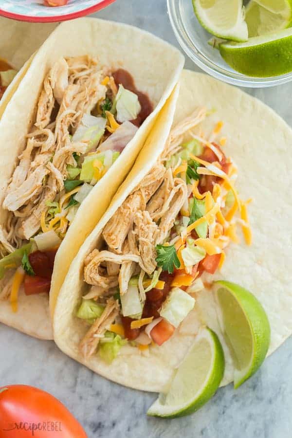 instant pot chicken tacos close up on flour tortillas with cheese lime wedges fresh tomatoes and lettuce