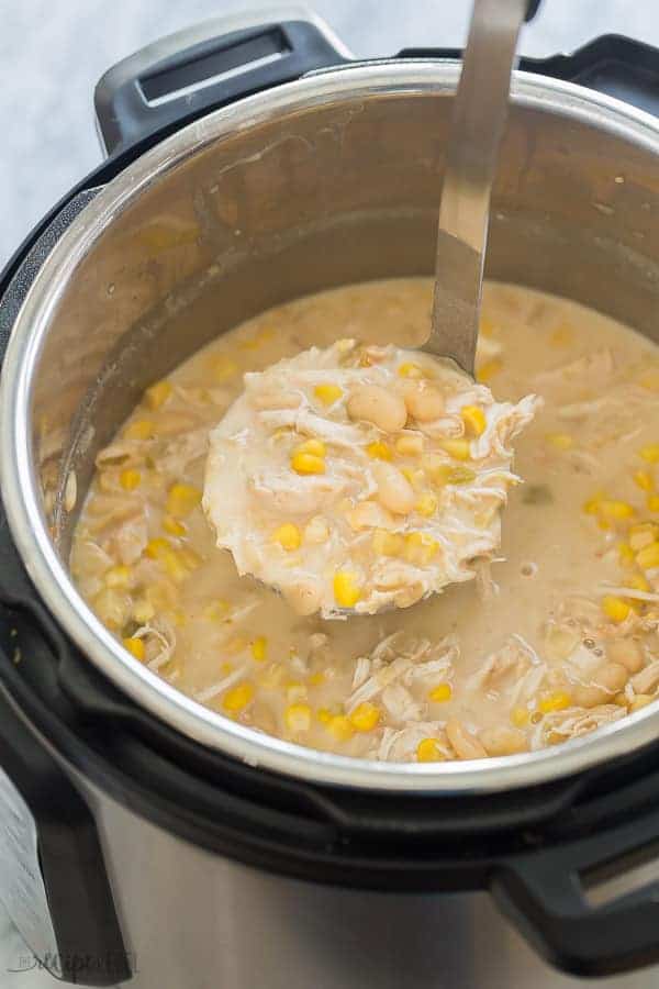 instant pot white chicken chili in pressure cooker with scoop pulling some out