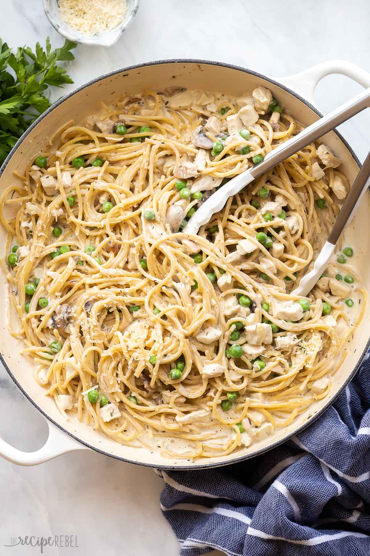 overhead image of one pot turkey tetrazzini in pan with tongs.