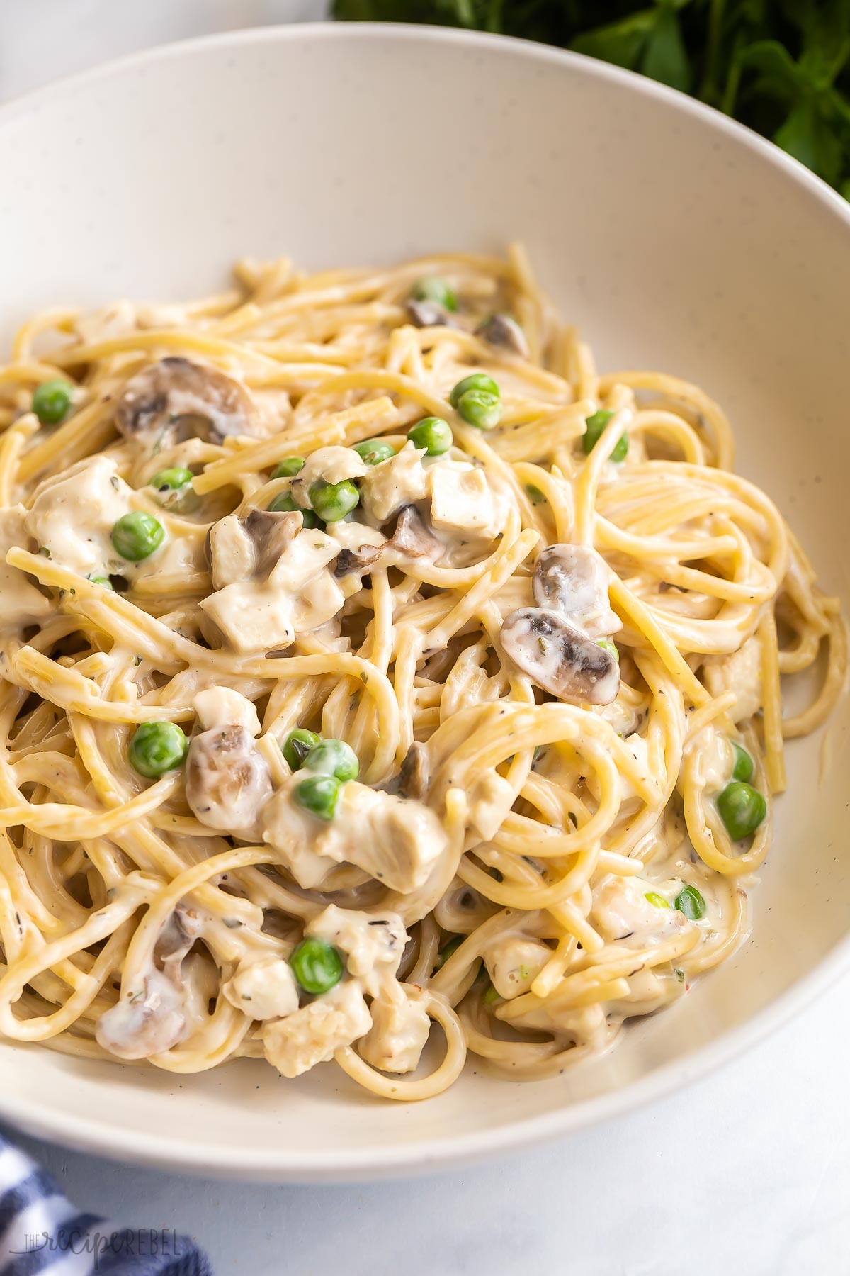 close up image of a plate of turkey tetrazzini with peas and mushrooms.