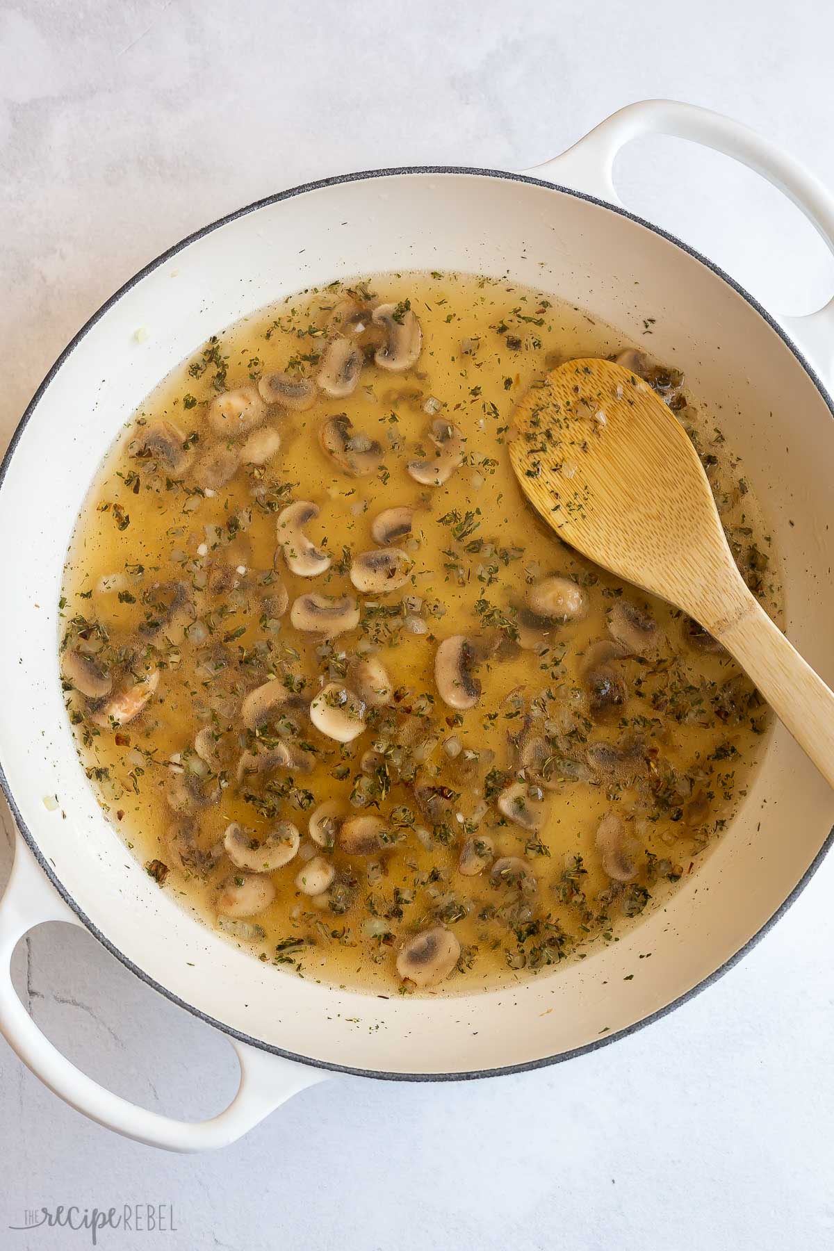 broth added to mushrooms and spices in pan.