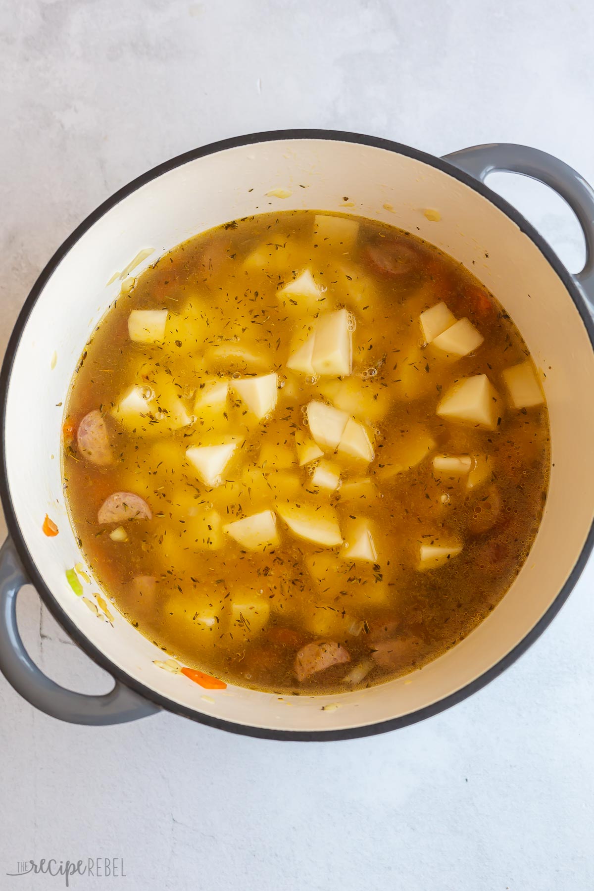 potatoes and broth added to soup in pot.