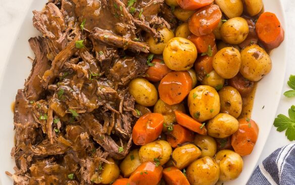 overhead image of shredded pot roast and potatoes and carrots on large white platter