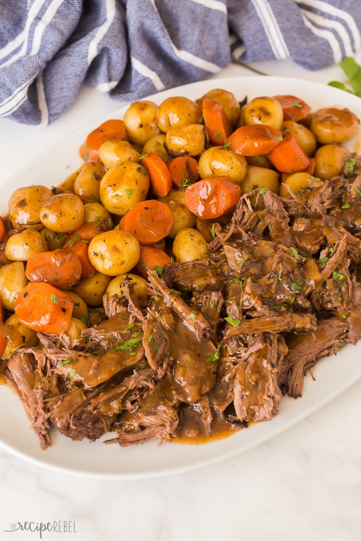 a platter of crockpot pot roast against a blue towel