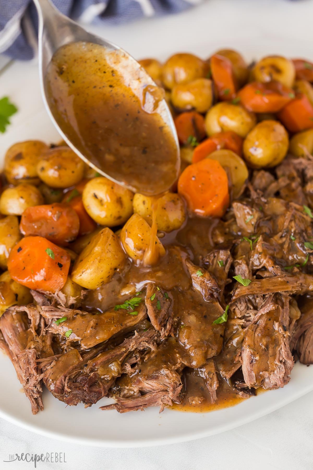 close up image of gravy being drizzled on slow cooker pot roast