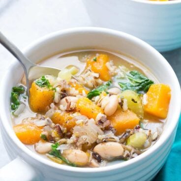 wild rice vegetable soup in white bowl with spoon