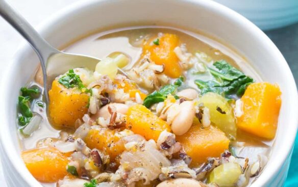 wild rice vegetable soup in white bowl with spoon