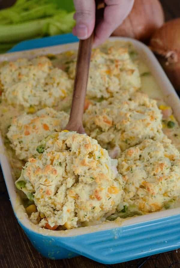 turkey biscuit casserole in blue baking dish with wooden spoon stuck in