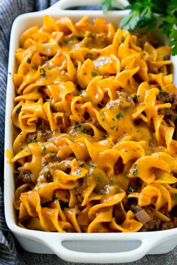 beef noodle casserole up close in white baking dish with cheddar cheese on top