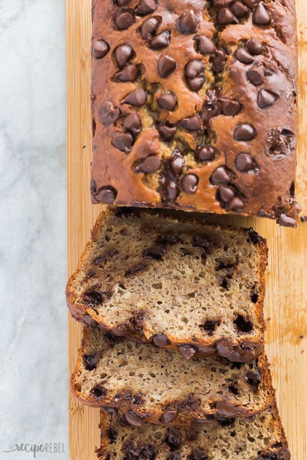 chocolate chip banana bread sliced on wooden cutting board on grey marble background