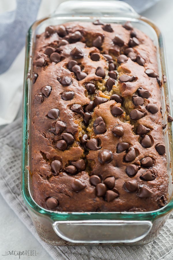 This Chocolate Chip Banana Bread recipe will be your new favorite! Perfect for breakfast, snacks, and lunch boxes. Super moist and made with one bowl and a whisk! #bread #baking #banana #chocolate #breakfast #recipe chocolate chip banana bread in loaf pan with lots of chocolate chips on top