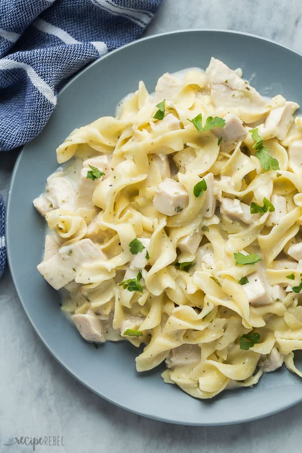 crockpot chicken noodles overhead on grey plate with fresh parsley garnish