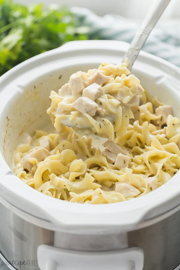 crockpot chicken and noodles in slow cooker with metal scoop pulling some out